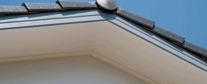Close-up of modern house fascias and soffits with dark roof tiles against clear blue sky
