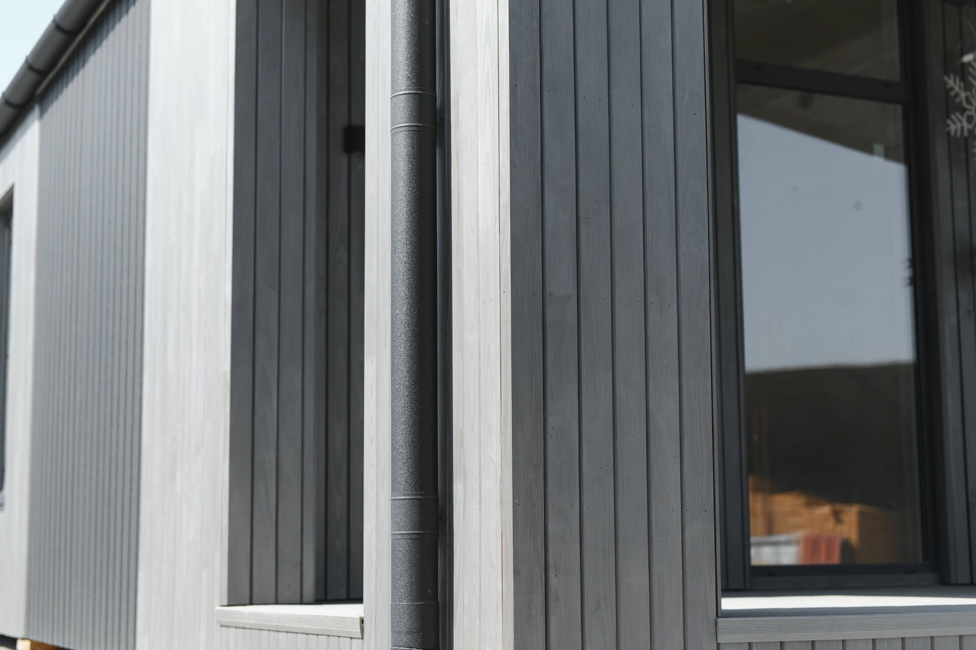 Modern building exterior with sleek vertical grey composite cladding and large window design.